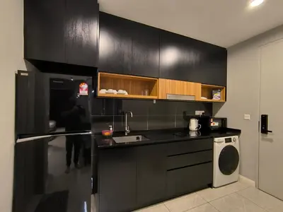 a kitchen with black cabinets and a washer and dryer at The Bukit Bintang Near pavilion Axon Residence KL in Kuala Lumpur