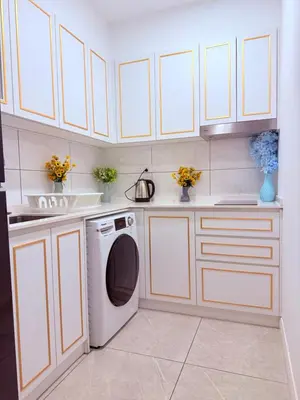 a kitchen with white cabinets and a washing machine at Aurora by comfort in Kuala Lumpur