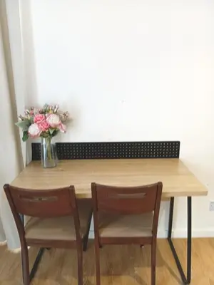 a wooden table with two chairs and a vase of flowers at Quill Residence relax Suites KLCC in Kuala Lumpur