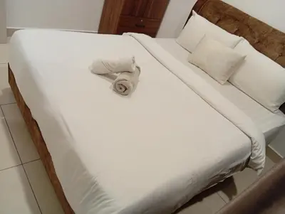a bed with white sheets and a towel on it at B&B at TRION KL in Kuala Lumpur