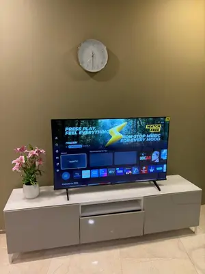 a flat screen tv sitting on a cabinet with a clock at sky suites klcc by afexten in Kuala Lumpur