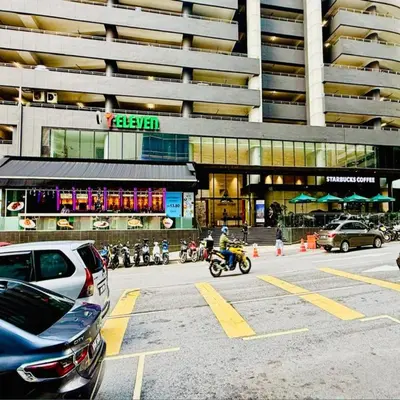a man riding a motorcycle in front of a building at sky suites klcc by Sweet home Apartment in Kuala Lumpur