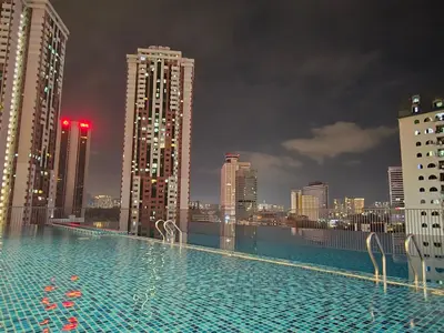 a swimming pool on top of a city skyline at night at KLCC SERVICED Suites CHAMBERS in Kuala Lumpur