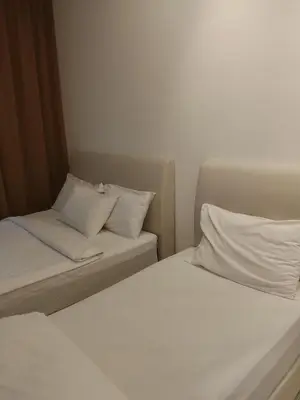 two beds in a room with white sheets and pillows at Kuala Lumpur Majestic Suites KLCC in Kuala Lumpur