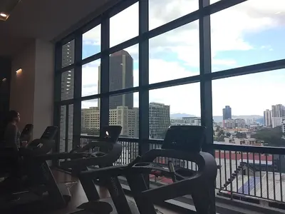 a gym with a view of the city from a large window at Kuala Lumpur Chambers Suites KLCC in Kuala Lumpur