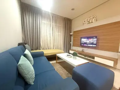 a living room with a blue couch and a tv at Soho Suites KLCC by MIMI in Kuala Lumpur