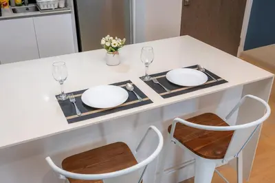 a kitchen counter with two white plates and two chairs at Star Residences One by The Conts in Kuala Lumpur