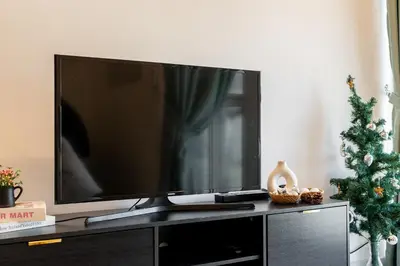 a flat screen tv sitting on a entertainment center with a christmas tree at The Atrium by The Conts in Kuala Lumpur