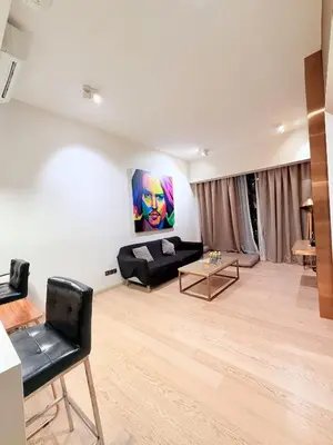 a living room with a black couch and a painting on the wall at Star Residence klcc by Aqua in Kuala Lumpur