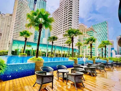 a hotel patio with tables and chairs and palm trees at Vortex suites Klcc near KL in Kuala Lumpur