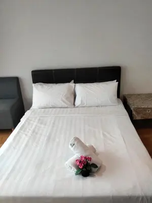 a white bed with a bouquet of flowers on it at Vortex suites Klcc near KL in Kuala Lumpur