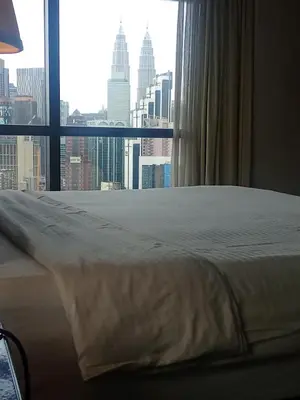 a bed in a room with a view of a city at Times square Suites at Time Square KL in Kuala Lumpur