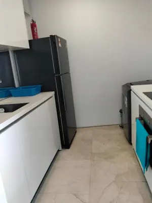 a kitchen with a black refrigerator and white cabinets at Vortex suites Klcc near KL Area in Kuala Lumpur