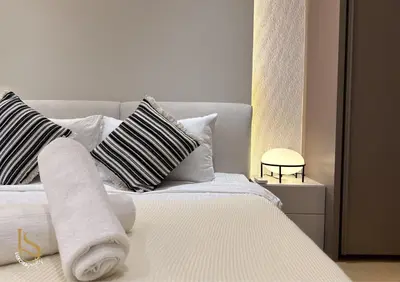 a white bed with black and white pillows on it at LUXURA SUITE's E A T O N KLCC in Kuala Lumpur