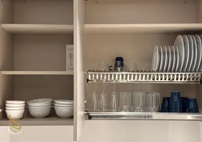 a kitchen cabinet with plates and bowls and glasses at LUXURA SUITE's E A T O N KLCC in Kuala Lumpur