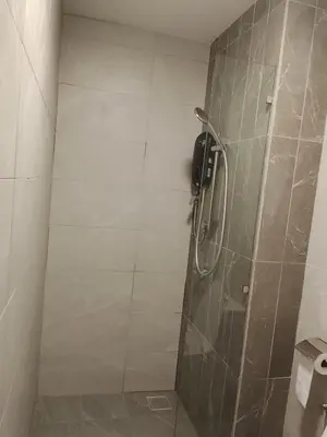 a bathroom with a shower with a tiled wall at Quill Luxury Suites KLCC in Kuala Lumpur