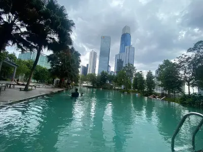 a person swimming in a pool of green water in a city at Agile Heaven Luxury Suite bukit bintang in Kuala Lumpur