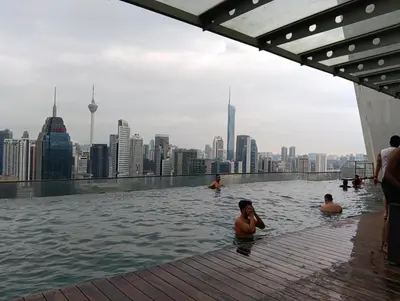 a group of people swimming in a infinity pool on the roof of a city at Female Hostel Regalia Residence in Kuala Lumpur