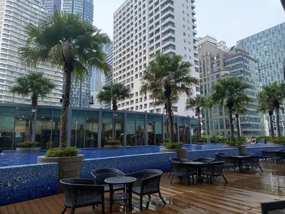 a courtyard with tables and palm trees in a city at Vortex Amira suites klcc Apartment in Kuala Lumpur