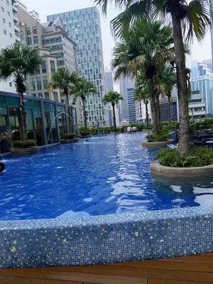 a large swimming pool with palm trees and buildings at Vortex Amira suites klcc Apartment in Kuala Lumpur