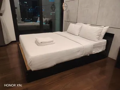 a bed with white sheets and towels on it at Opus Residence KL118 By Millennium Suite in Kuala Lumpur