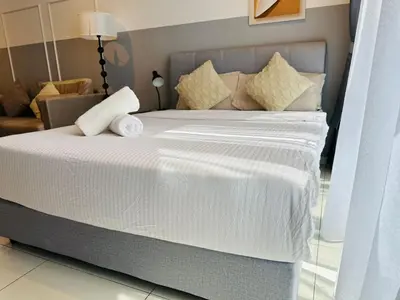 a bed with white sheets and pillows in a room at Majestic Suites klcc By EQ in Kuala Lumpur