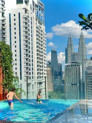 two children playing in a swimming pool in a city at Grand Suites KLCC By Majestic Residence in Kuala Lumpur