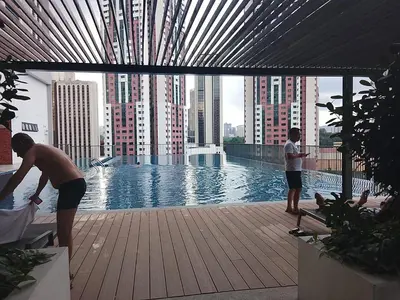 two men standing next to a swimming pool in a building at Chamber Klcc Suites Luxury Home in Kuala Lumpur