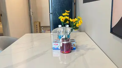 a table with a vase with yellow flowers in it at Majestic Suites KLCC by Aman Tokyo in Kuala Lumpur