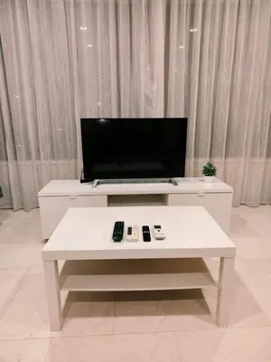 a living room with a white table with remote controls at Vortex Suite Klcc By Sky Moon in Kuala Lumpur