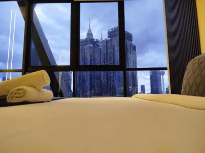 a bed with a view of a city from a window at Scarletz suites Klcc by Sunlight in Kuala Lumpur