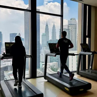 two people walking on treadmill in a gym looking out the window at Infinity pool luxury Apartment Axon in Kuala Lumpur