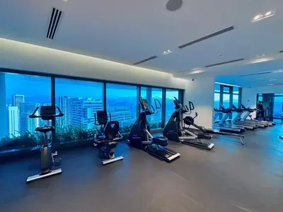 a gym with treadmills and ellipticals in a building with windows at Eaton Residences By Tropika KLCC in Kuala Lumpur