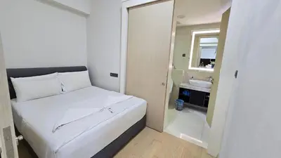 a small bedroom with a white bed and a bathroom at KL Suites At Star KLCC in Kuala Lumpur