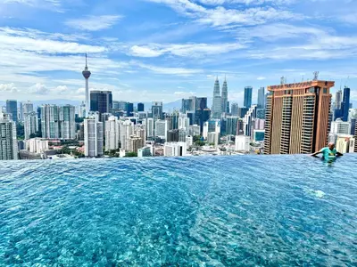 a woman sitting in a infinity pool overlooking a city at Glowing Star Home Infinity Swimming Pool By Lalaport in Kuala Lumpur