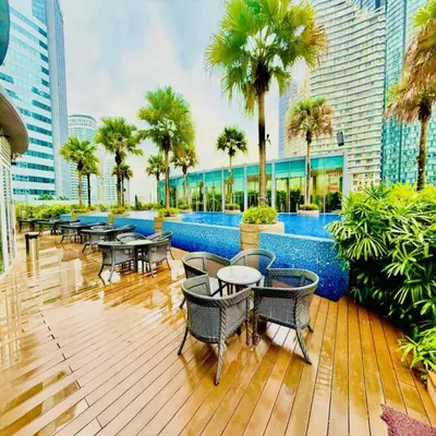 a deck with tables and chairs and a swimming pool at Vortex klcc by DMK Luxury suites Apartment in Kuala Lumpur