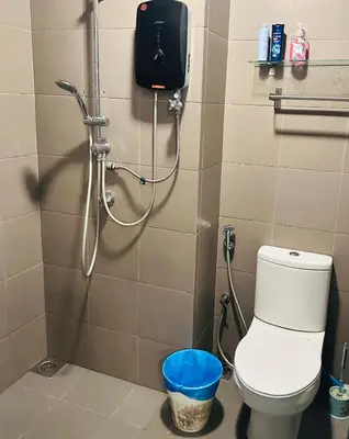 a bathroom with a shower with a toilet and a trash can at LuxeHive Stay in Kuala Lumpur