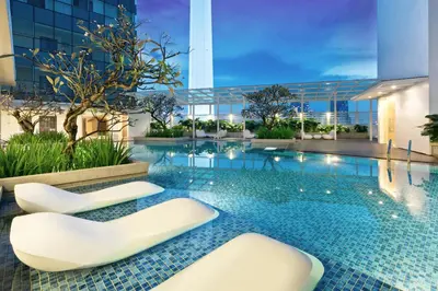 a swimming pool with two white chairs in a building at Oasia Suites Kuala Lumpur by Far East Hospitality in Kuala Lumpur