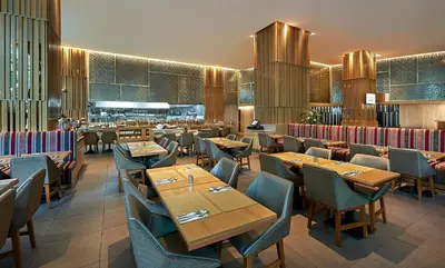 a dining room with wooden tables and chairs at Oasia Suites Kuala Lumpur by Far East Hospitality in Kuala Lumpur