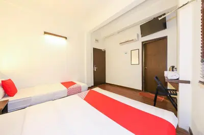 a hotel room with two beds and a desk at Hotel O Madras in Kuala Lumpur