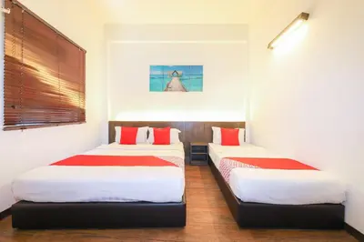 two beds in a room with white walls and red pillows at Hotel O Madras in Kuala Lumpur
