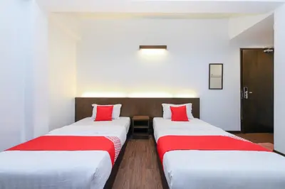 two beds in a hotel room with red pillows at Hotel O Madras in Kuala Lumpur