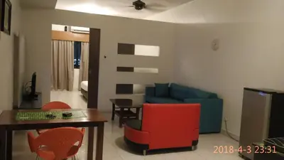 a living room with a blue couch and red chairs at Richone Maluri Private Hotel in Kuala Lumpur