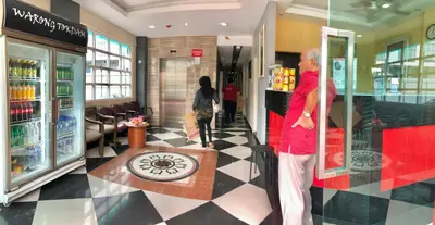 a man is standing in a store with a counter at Adamson Park Kuala Lumpur in Kuala Lumpur