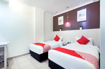 two beds in a hotel room with red accents at OYO 761 City Hotel in Kuala Lumpur