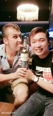two young men sitting next to each other holding a bottle at City Inn Hotel in Kuala Lumpur
