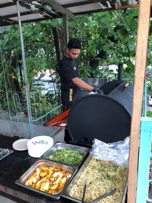 a man standing in front of a table with food at Chinatown Hostel by Mingle - Rooftop Private Jacuzzi with Bar in Kuala Lumpur