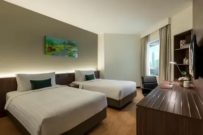 a hotel room with two beds and a desk at Oakwood Hotel & Residence Kuala Lumpur in Kuala Lumpur
