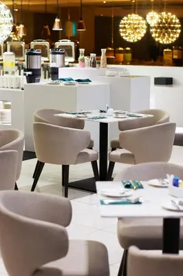 a restaurant with white tables and chairs and chandeliers at Cosmo Hotel Kuala Lumpur in Kuala Lumpur