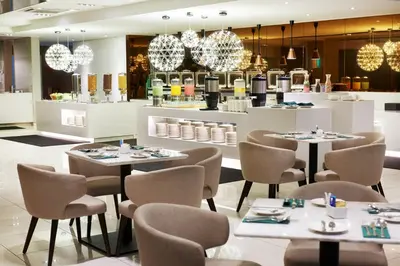 a restaurant with tables and chairs and chandeliers at Cosmo Hotel Kuala Lumpur in Kuala Lumpur